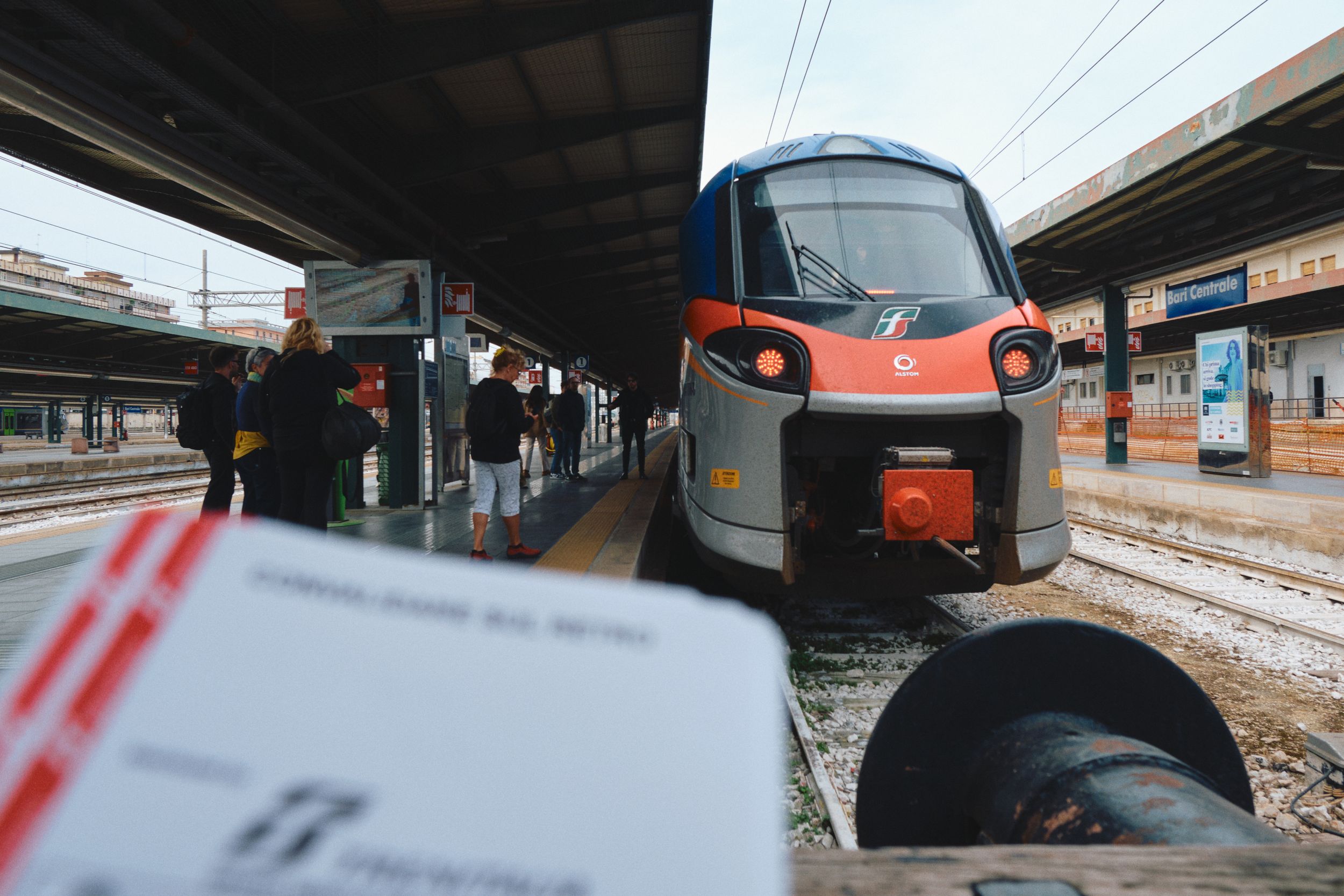 A modern red and white train waiting at a snowy station platform.
