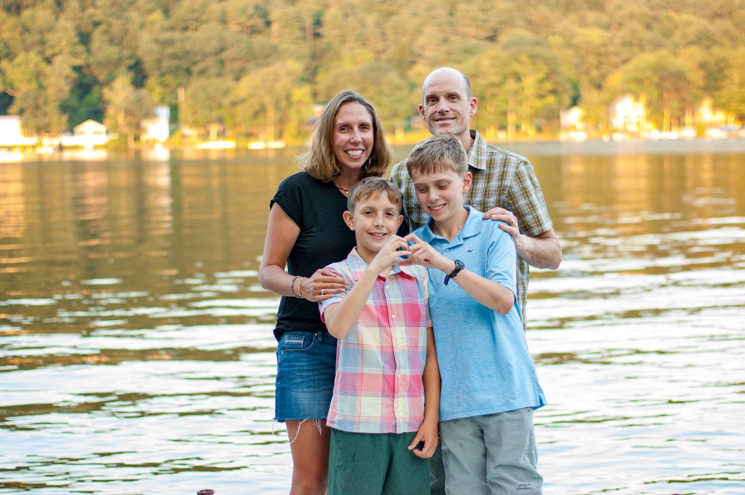 Family enjoying a sunset moment by a lake with golden reflections on the water in the background.