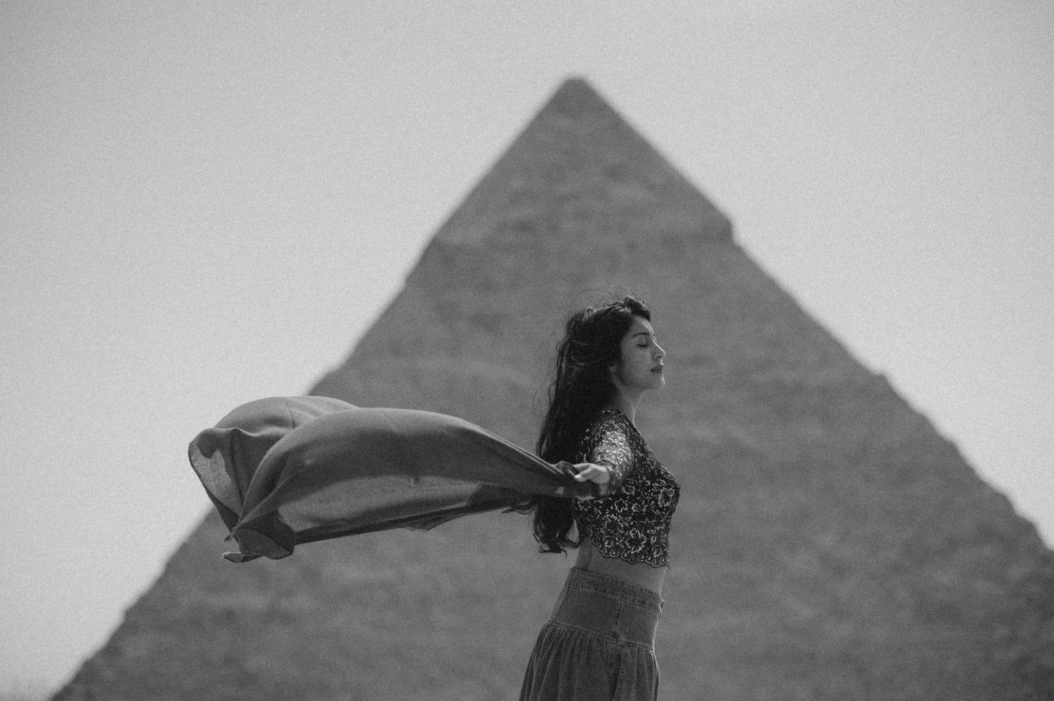 Artistic black and white portrait with flowing fabric against the pyramid silhouette.