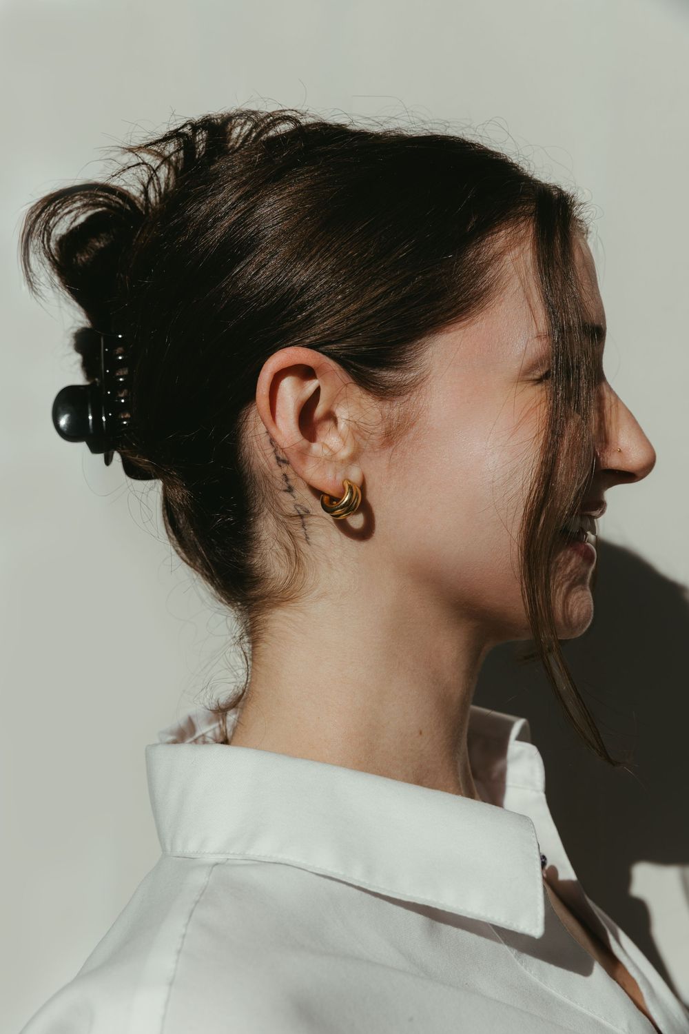 Woman's side profile showing off gold earrings as she smiles during branding session.