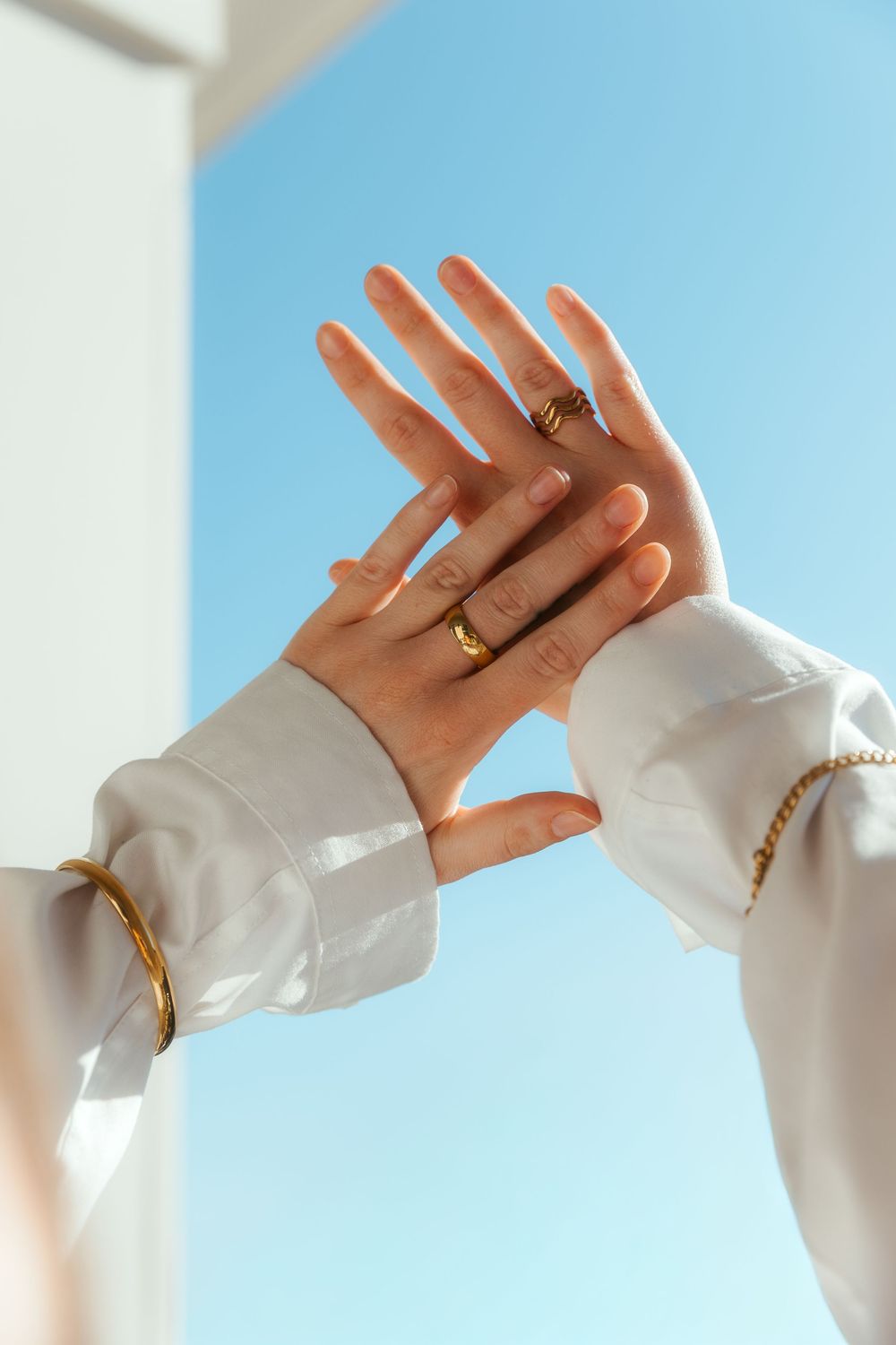 Jewelry branding shoot, hands against the sky to show off gold jewelry.