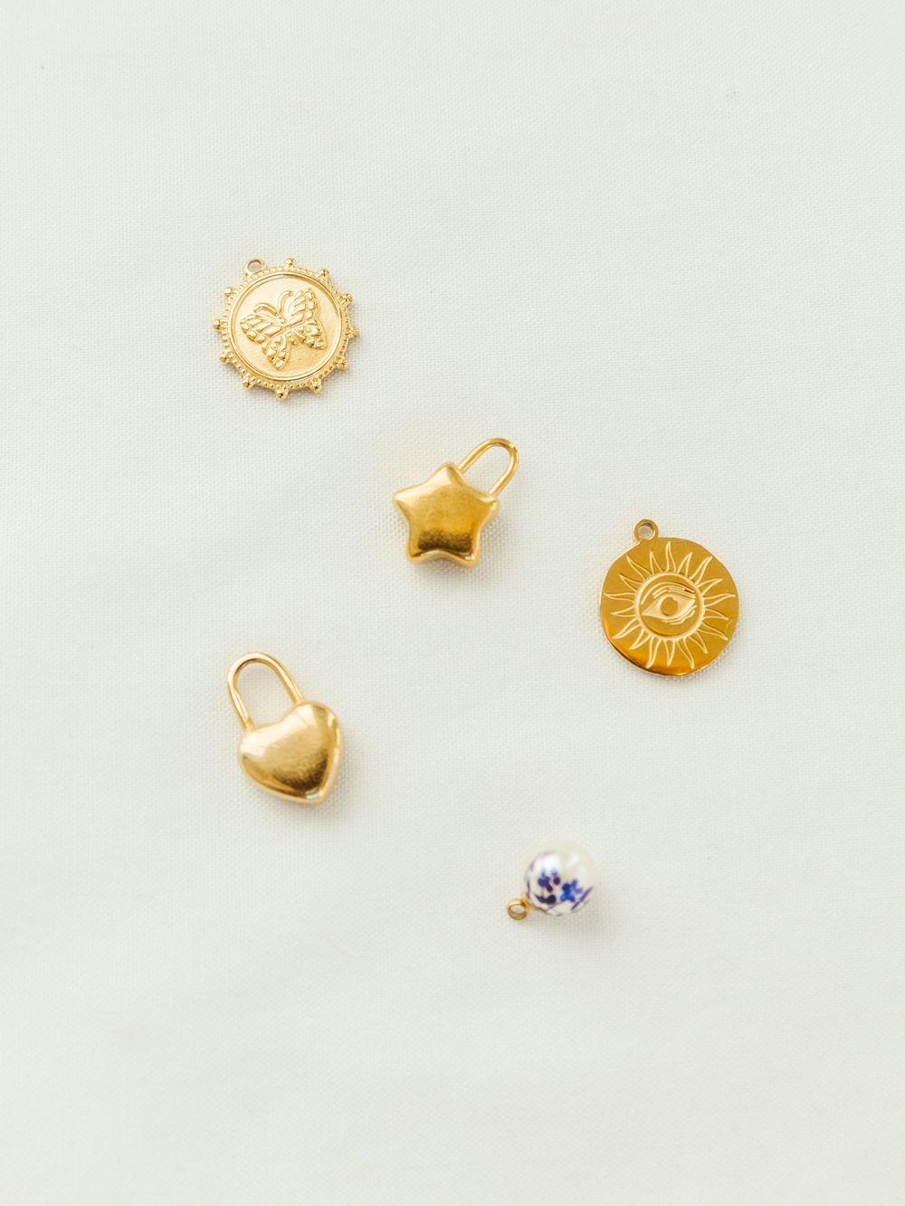 Gold charms scattered across background during branding shoot for jewelry brand.