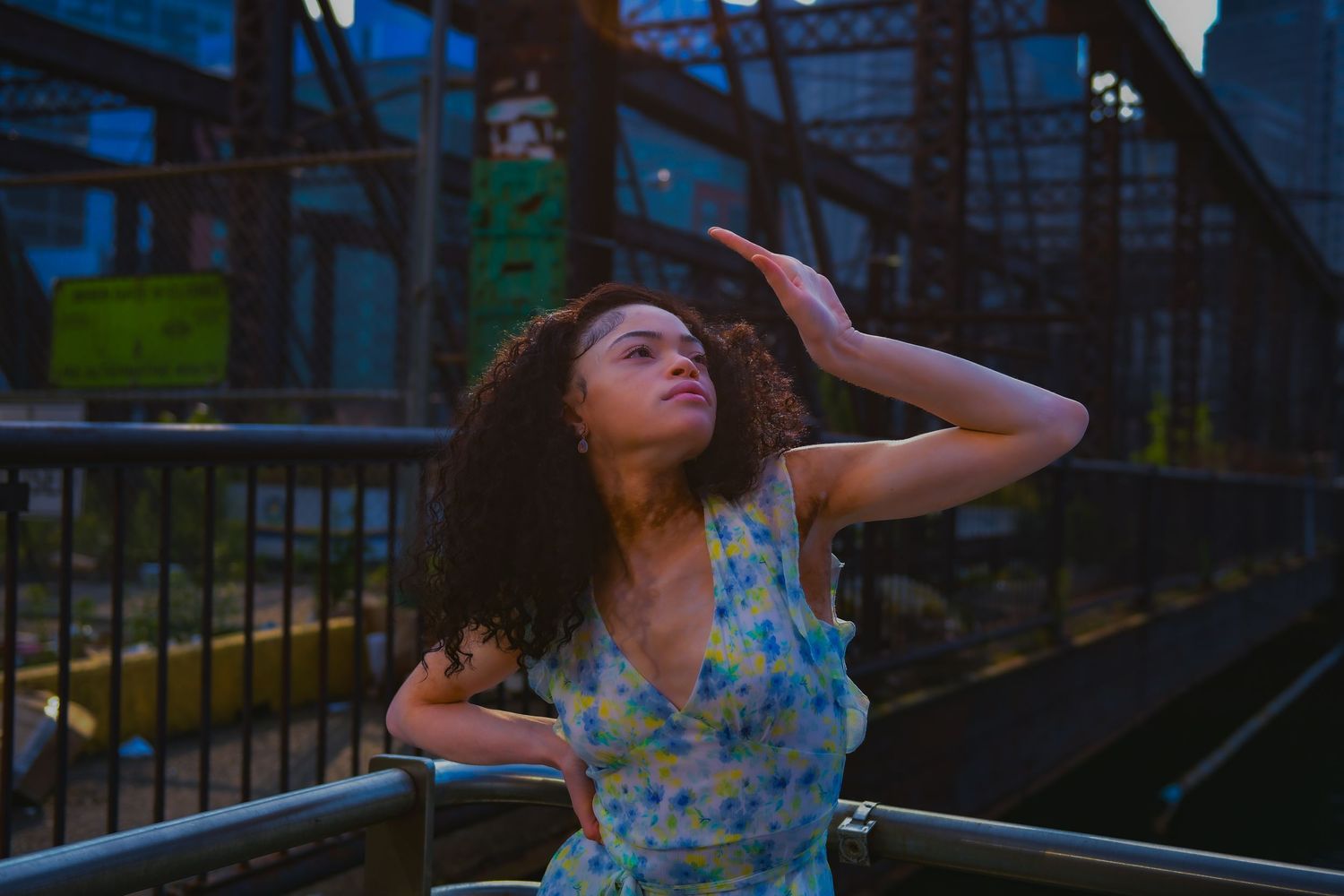 Artistic portrait at dusk with industrial architecture backdrop.