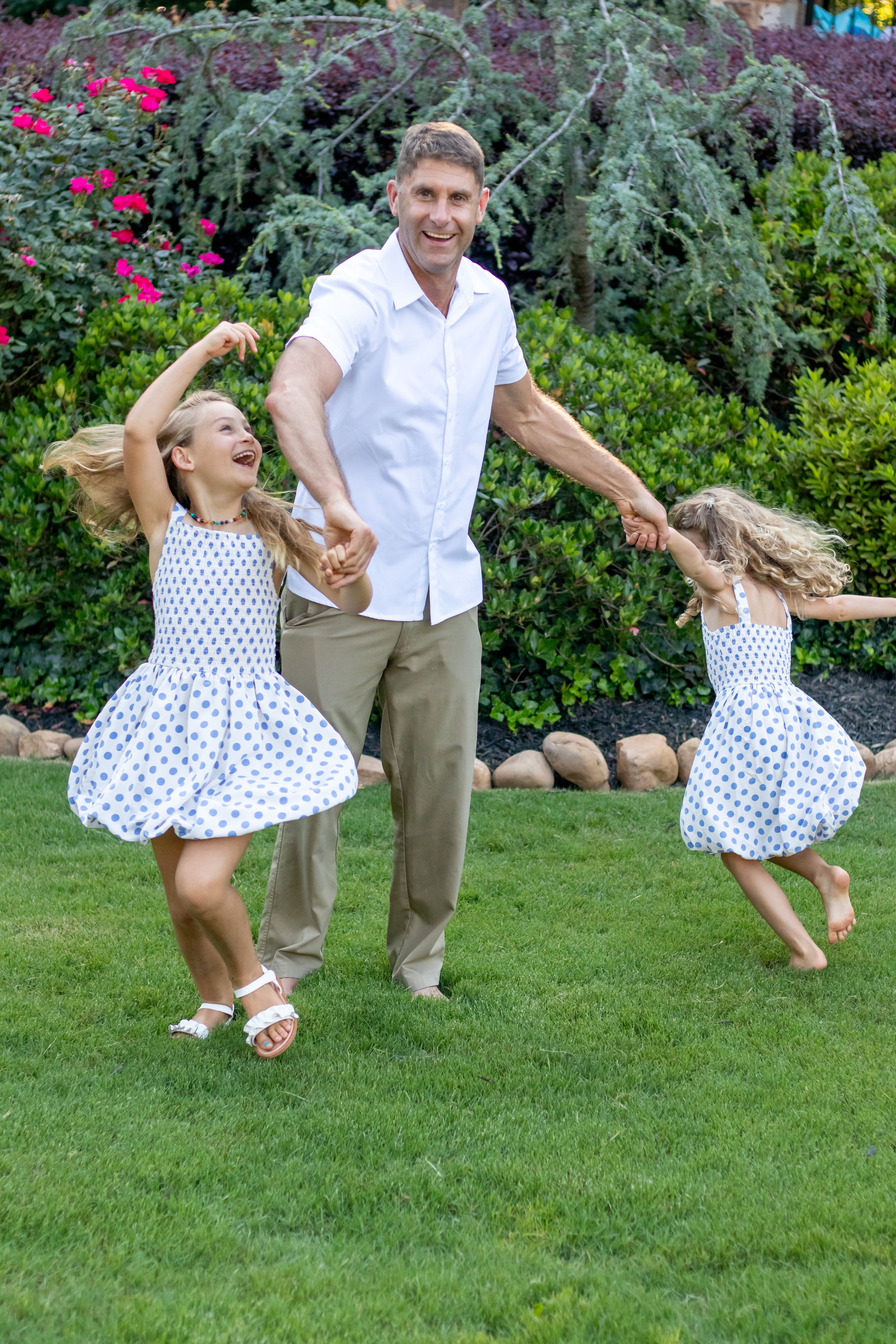 dad and spinning two daughters around in the grass family session Acworth, Georgia