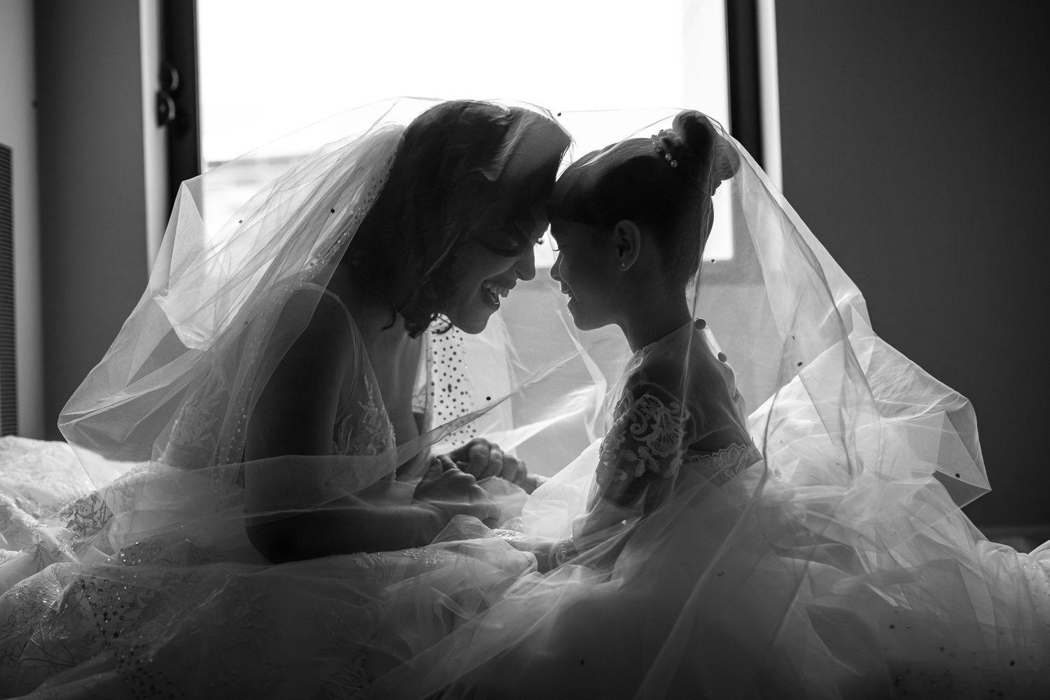 Intimate black and white moment of two people sharing a tender moment under wedding veils.