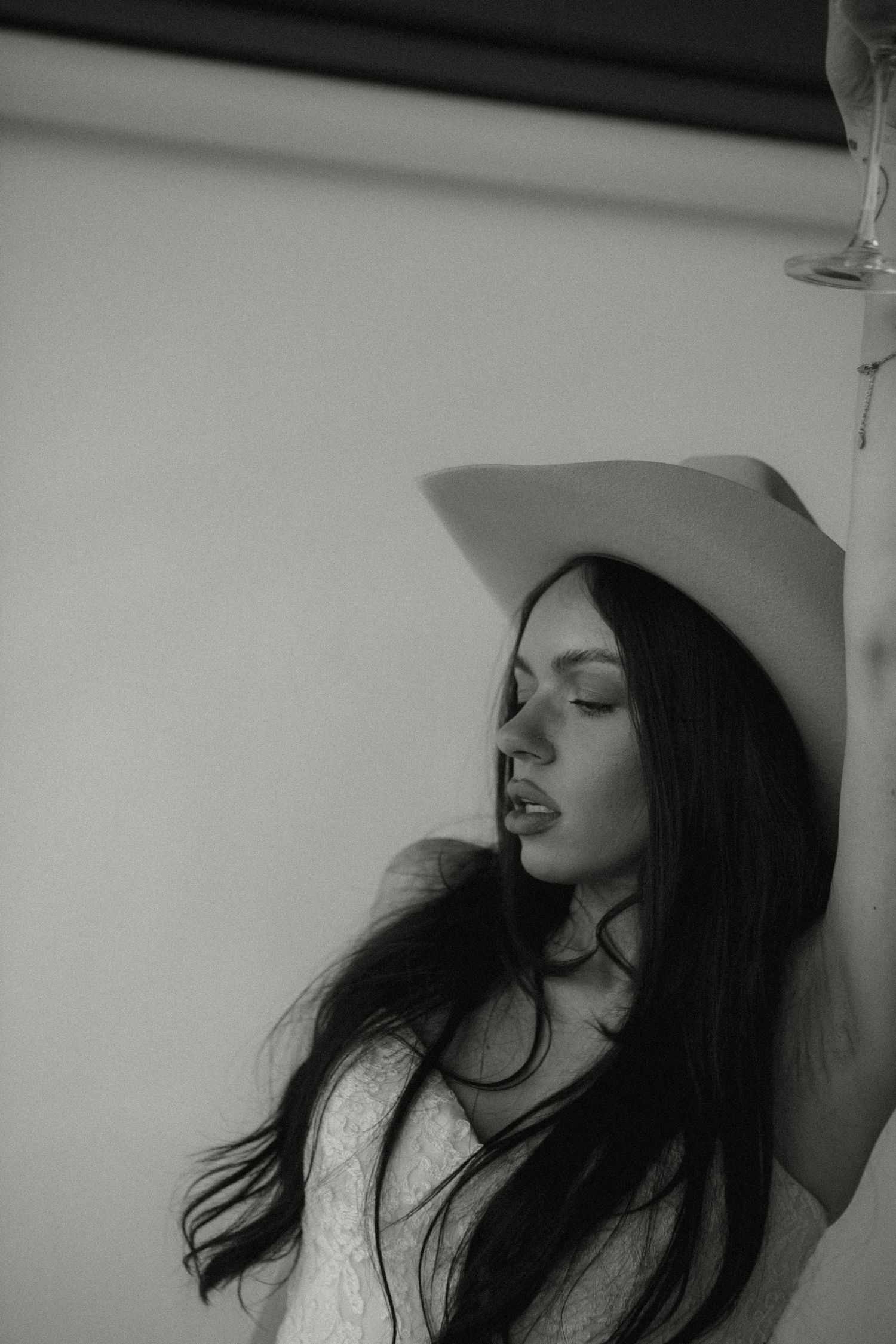 Artistic black and white side profile of bride wearing cowboy hat and lace dress.