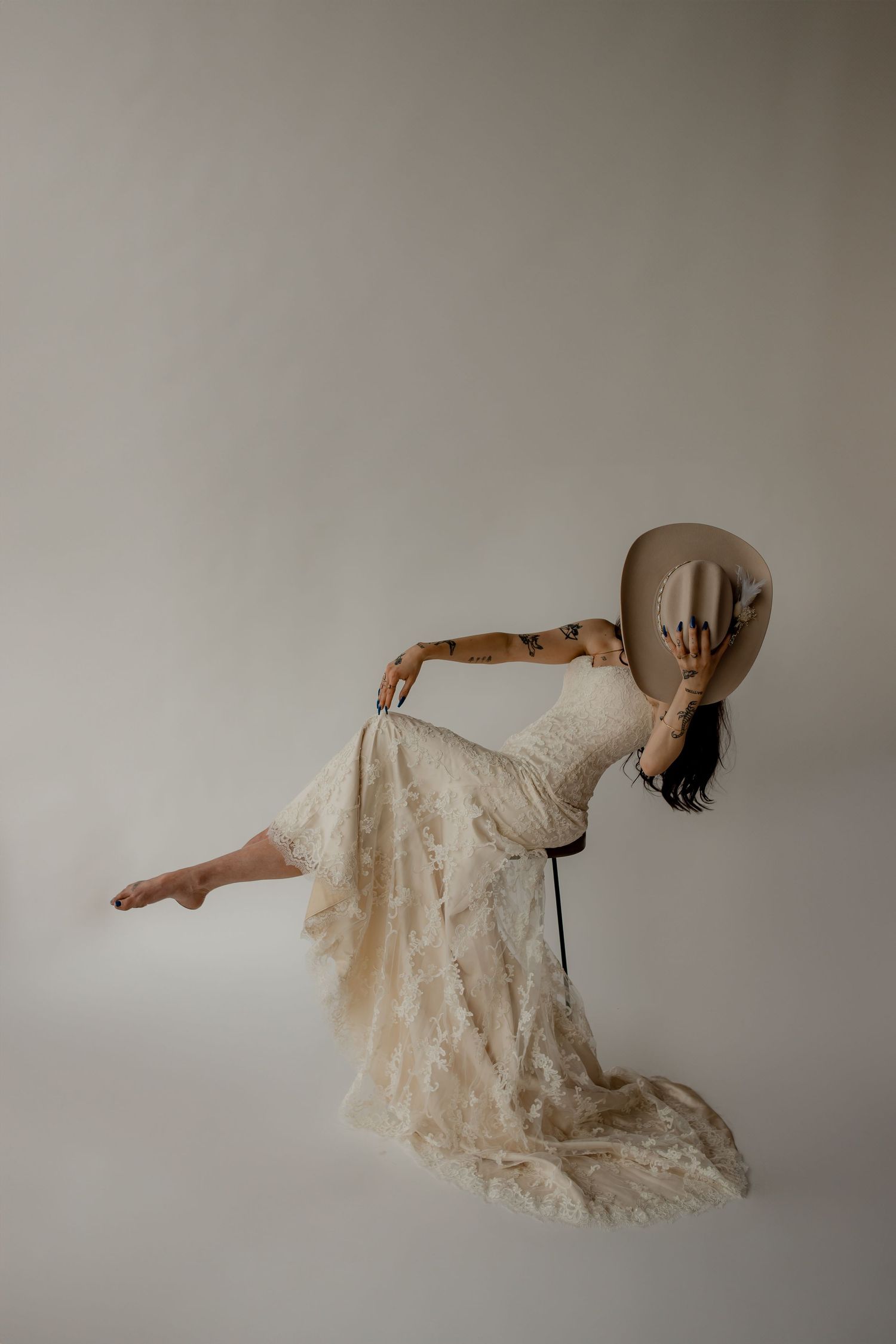 A graceful bride in western attire leans back in a dramatic pose against a simple background.