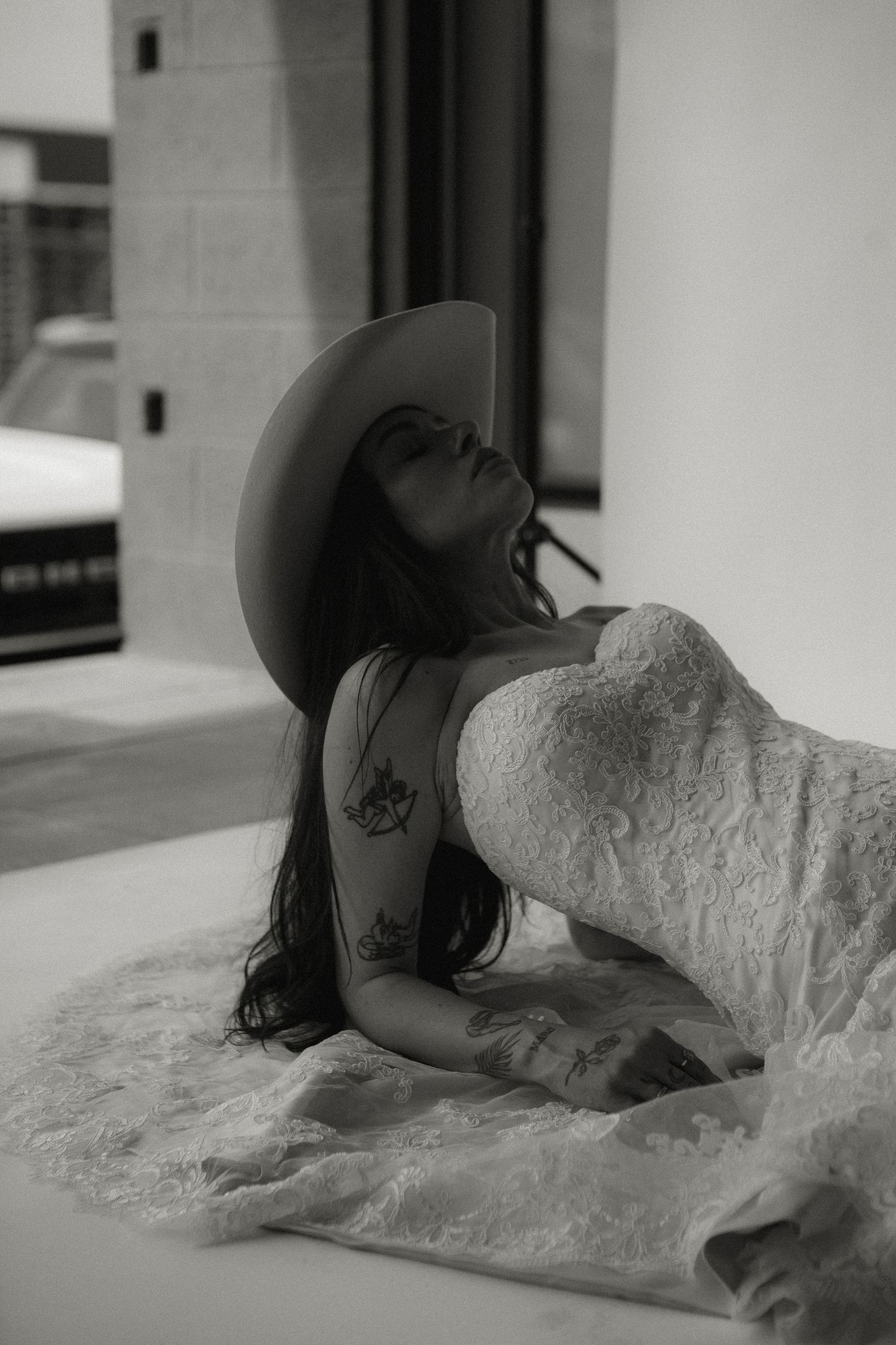 Moody black and white photo of bride in western attire leaning back.