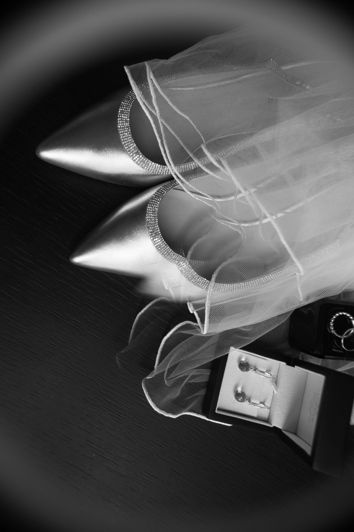 Black and white still life of bridal accessories including sparkly heels and jewelry.