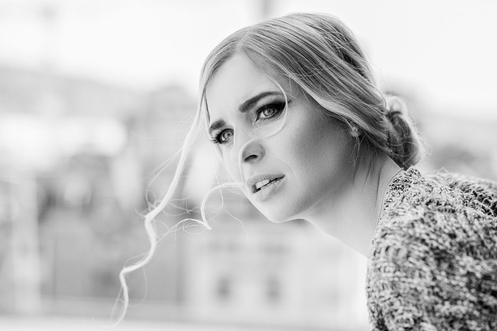 Black and white close-up of a blonde woman with dramatic eye makeup and soft wavy hair.