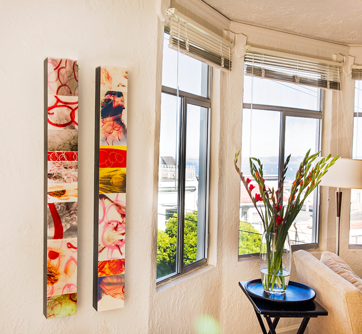 Modern coastal room with artistic vertical wall panels, bay windows, and fresh flowers in a blue vase on side table.