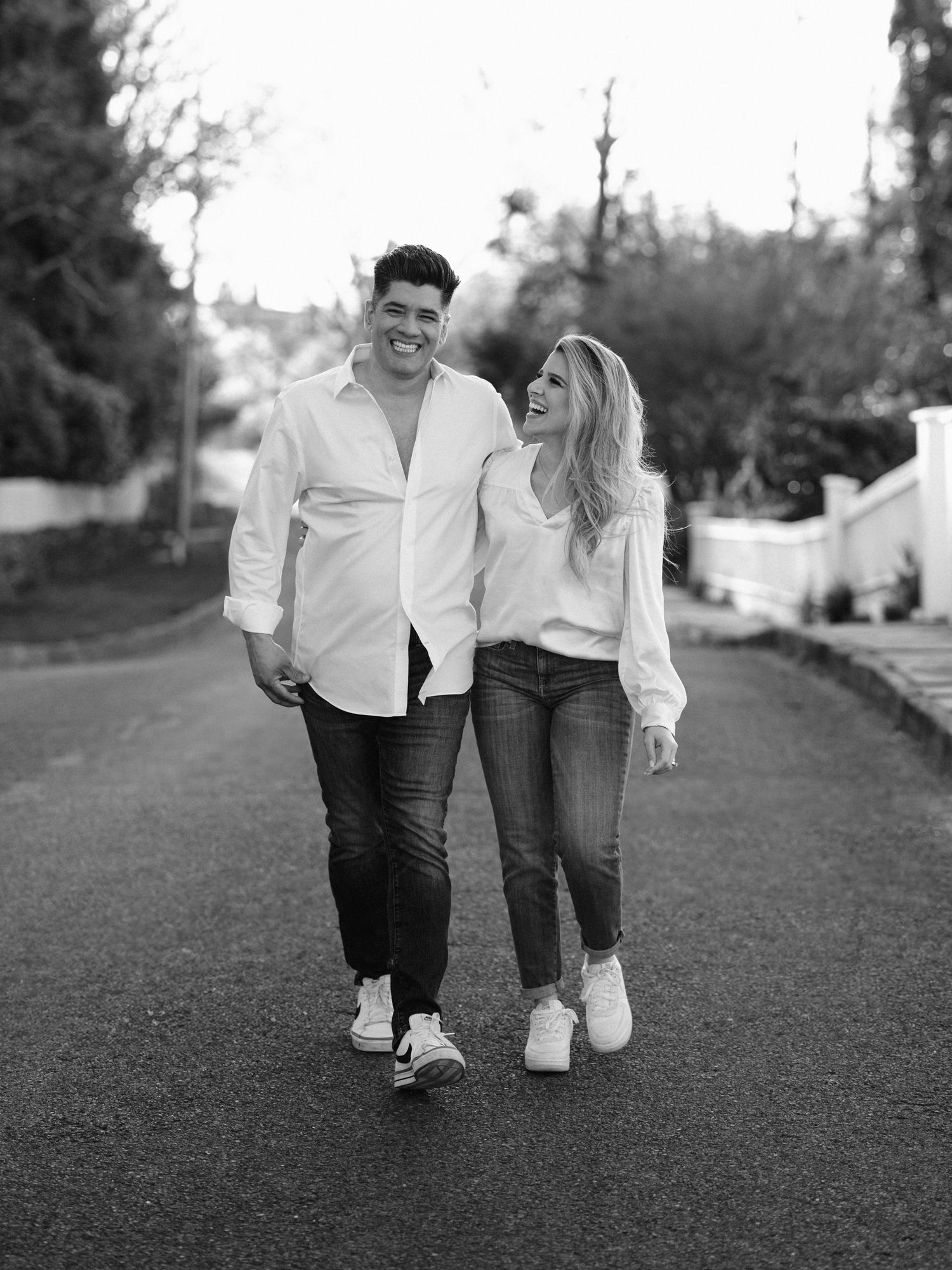 Black and white portrait of couple in casual attire walking on residential street.
