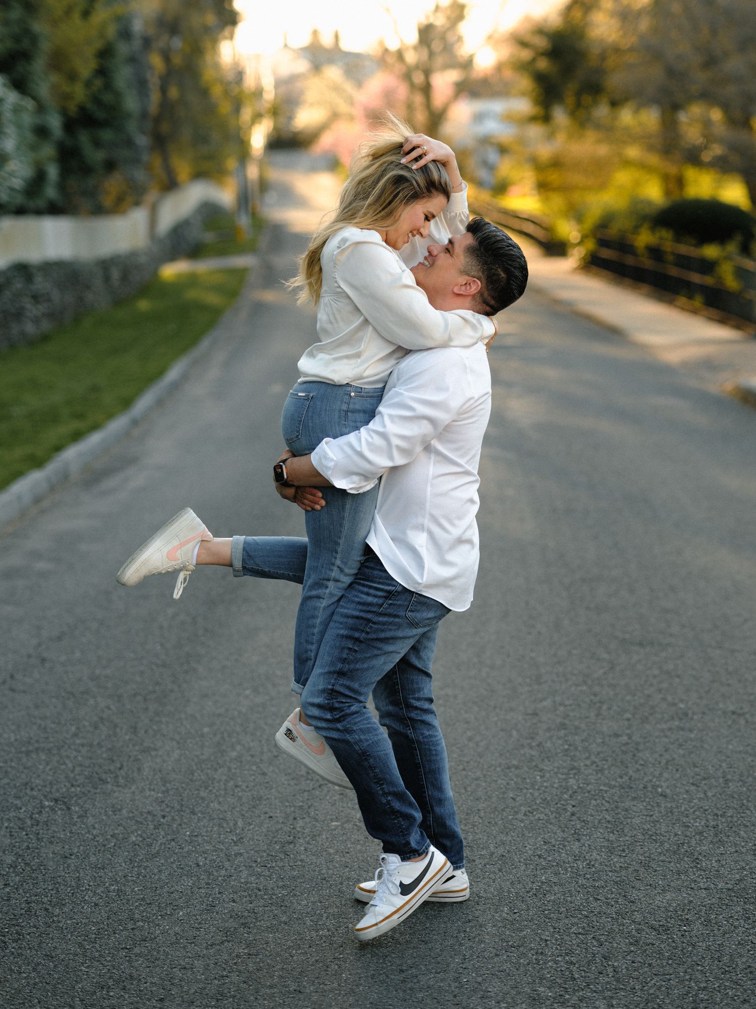 Couple dancing together on a paved road wearing coordinated casual outfits.