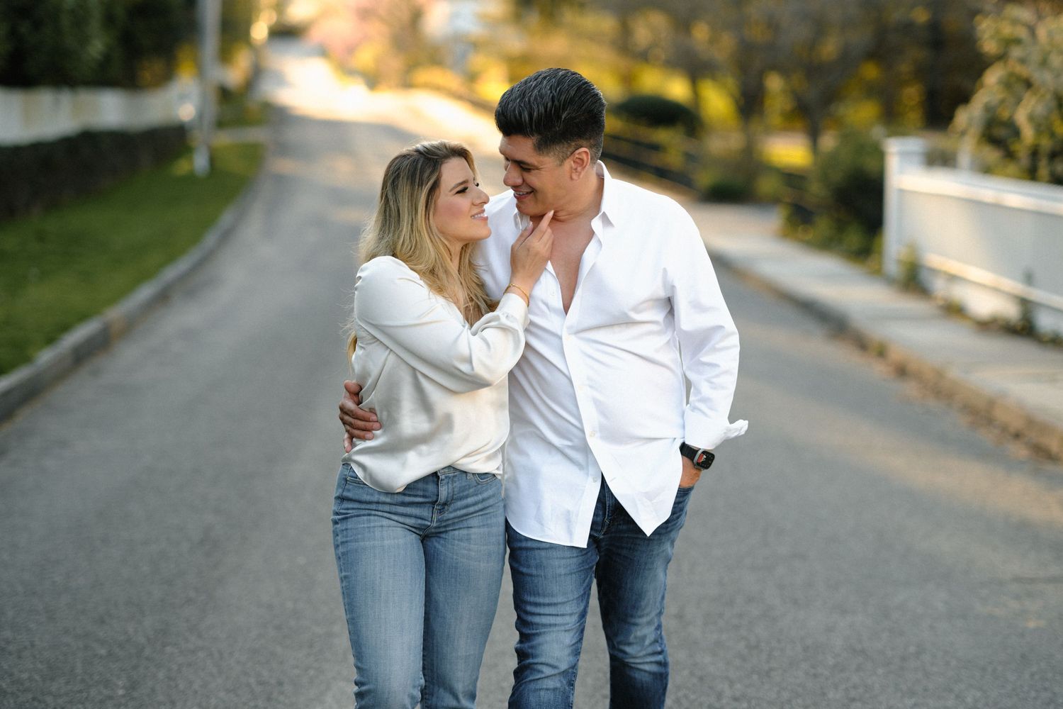 Couple sharing a romantic moment while walking together on a street during golden hour.