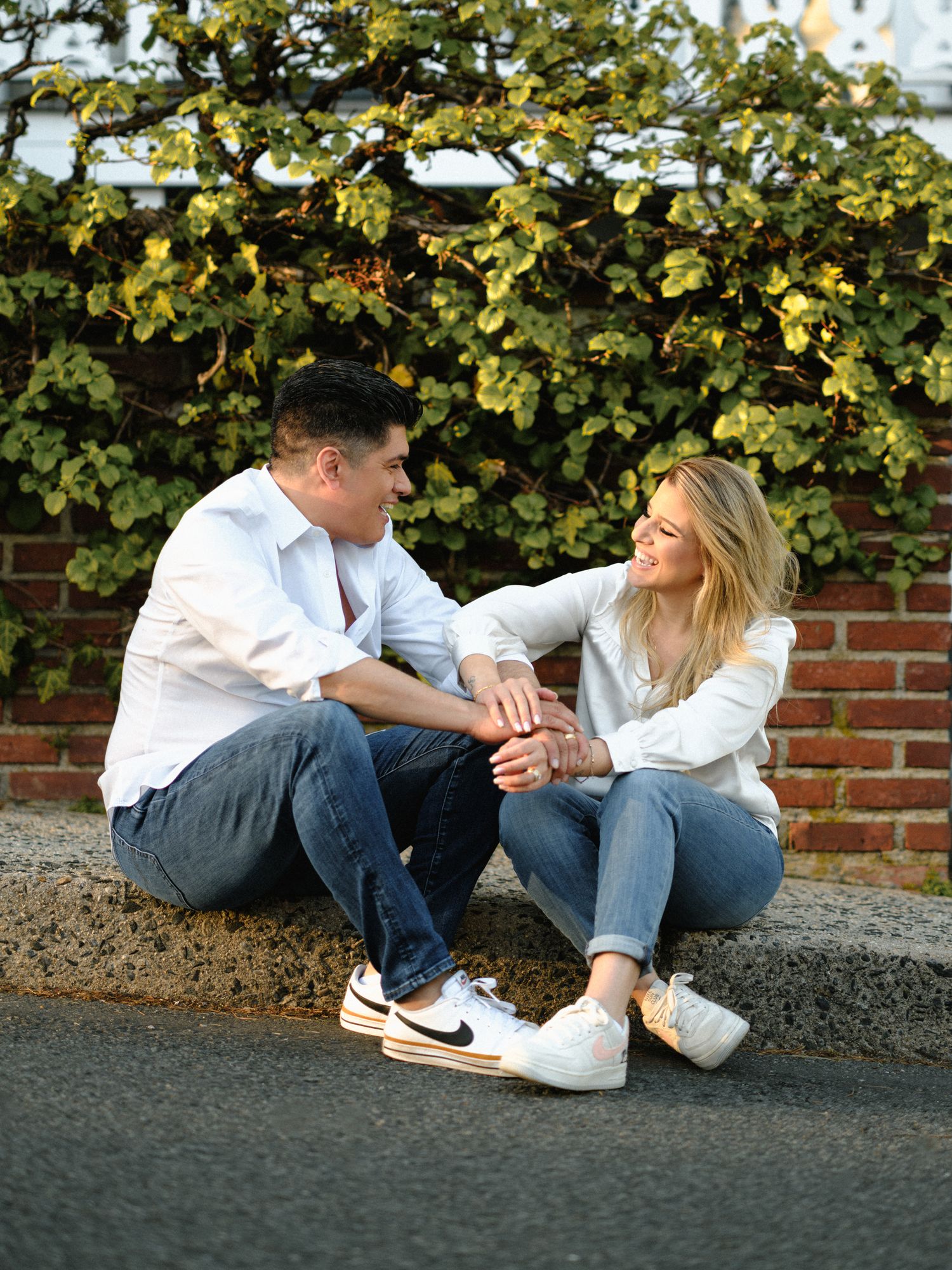 Couple in casual wear sitting together on a curb having an intimate moment.