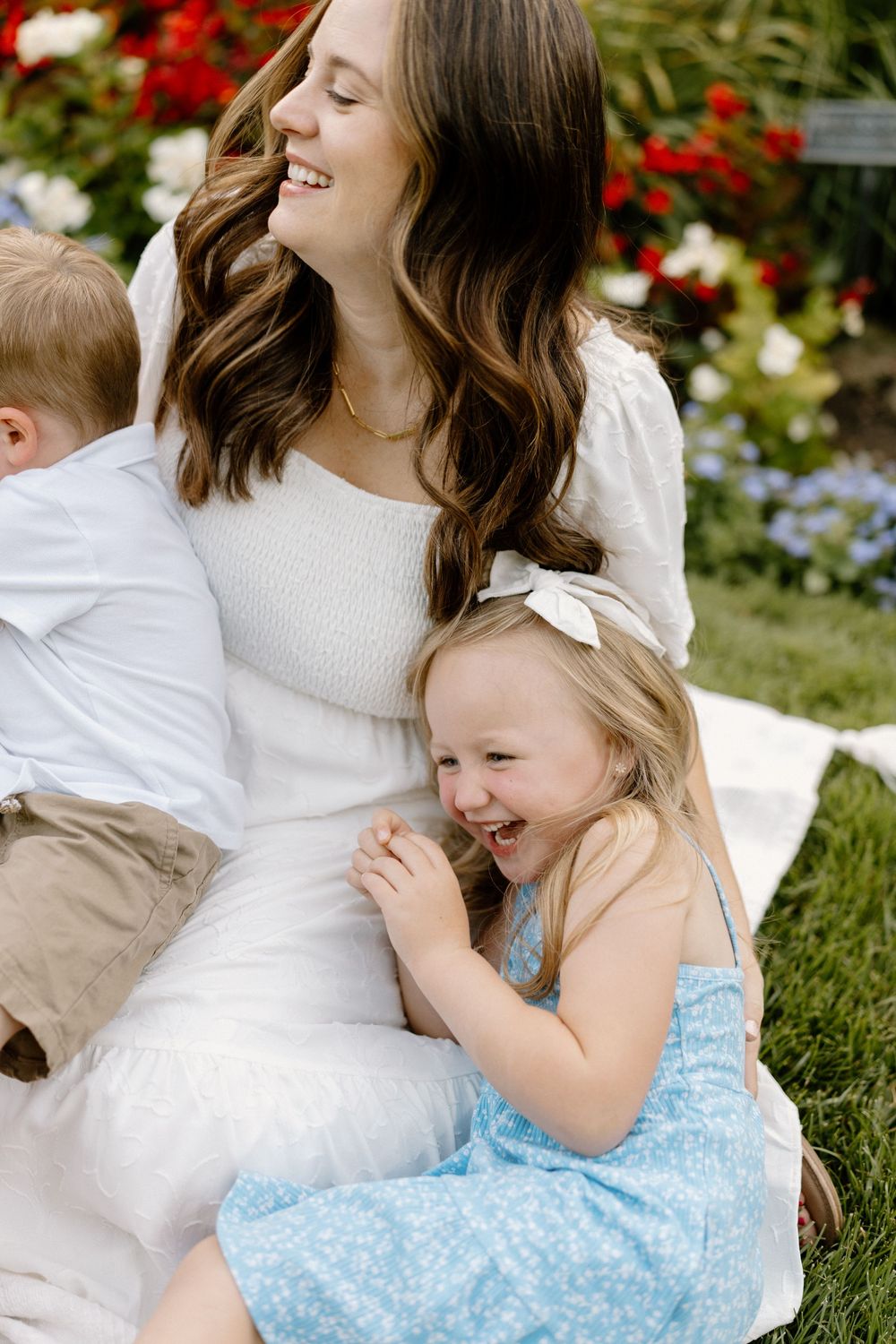 Family sharing tender moments and laughter together in a garden with red flowers.