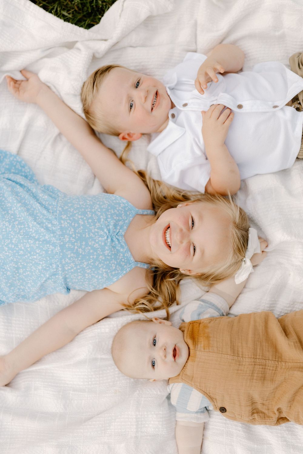 A series of candid shots showing a child lying on white bedding with bright expressions and natural lighting.