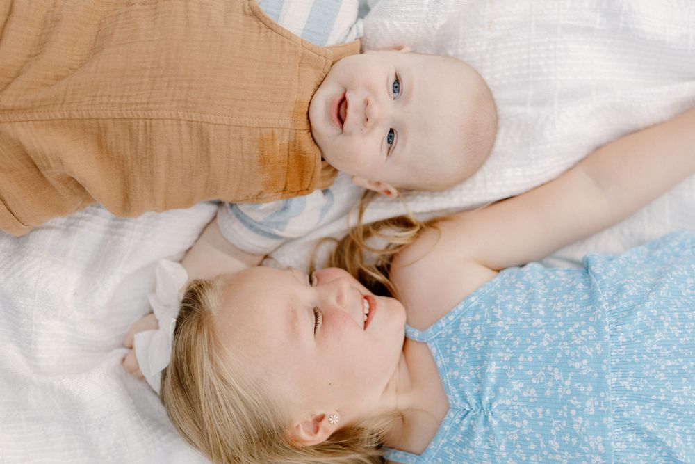 Parent and baby lie on a blue blanket sharing tender moments in a series of connected photos.