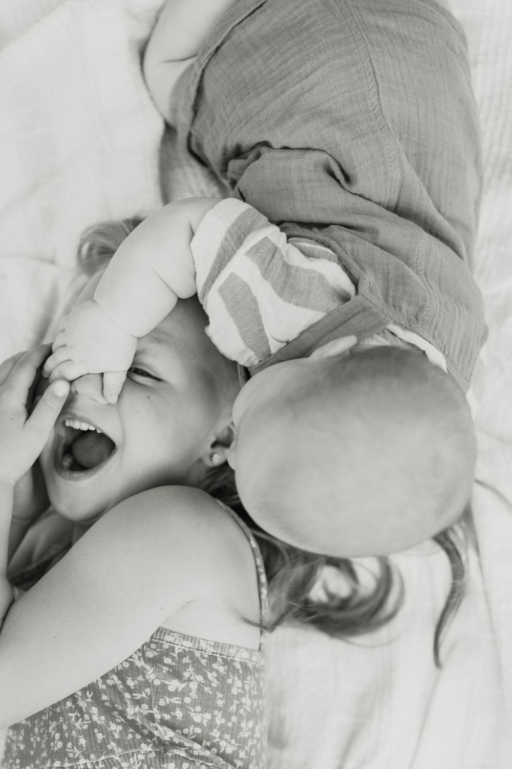 Artistic black and white series of candid family moments on white bedding.