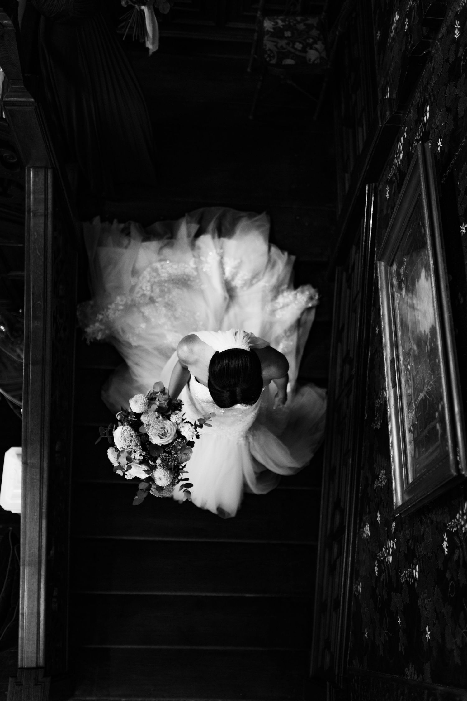 bridesmaid helping the bride carry her dress down the grand staircase at the highfield house