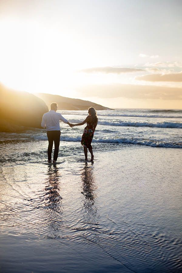 Affectionate couple holding hands during a sunset walk on the beach (Melbourne couples photography by Lesley Marks)