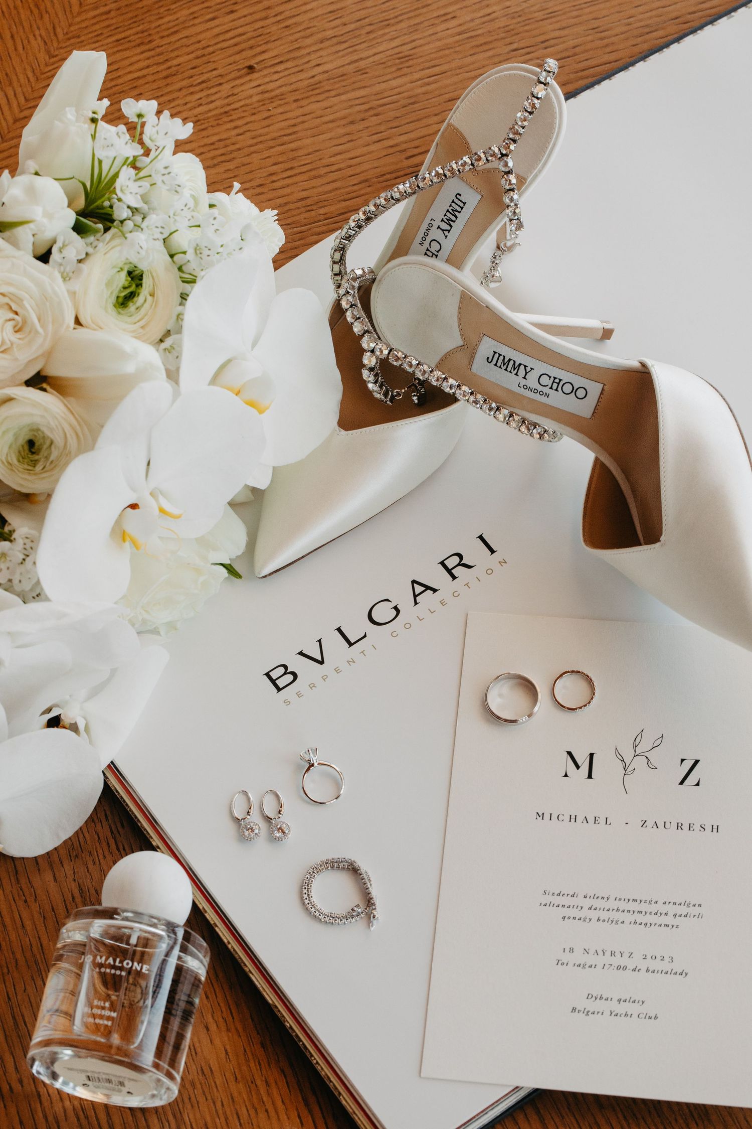 Flat lay of wedding rings, shoes, invitations, and flowers