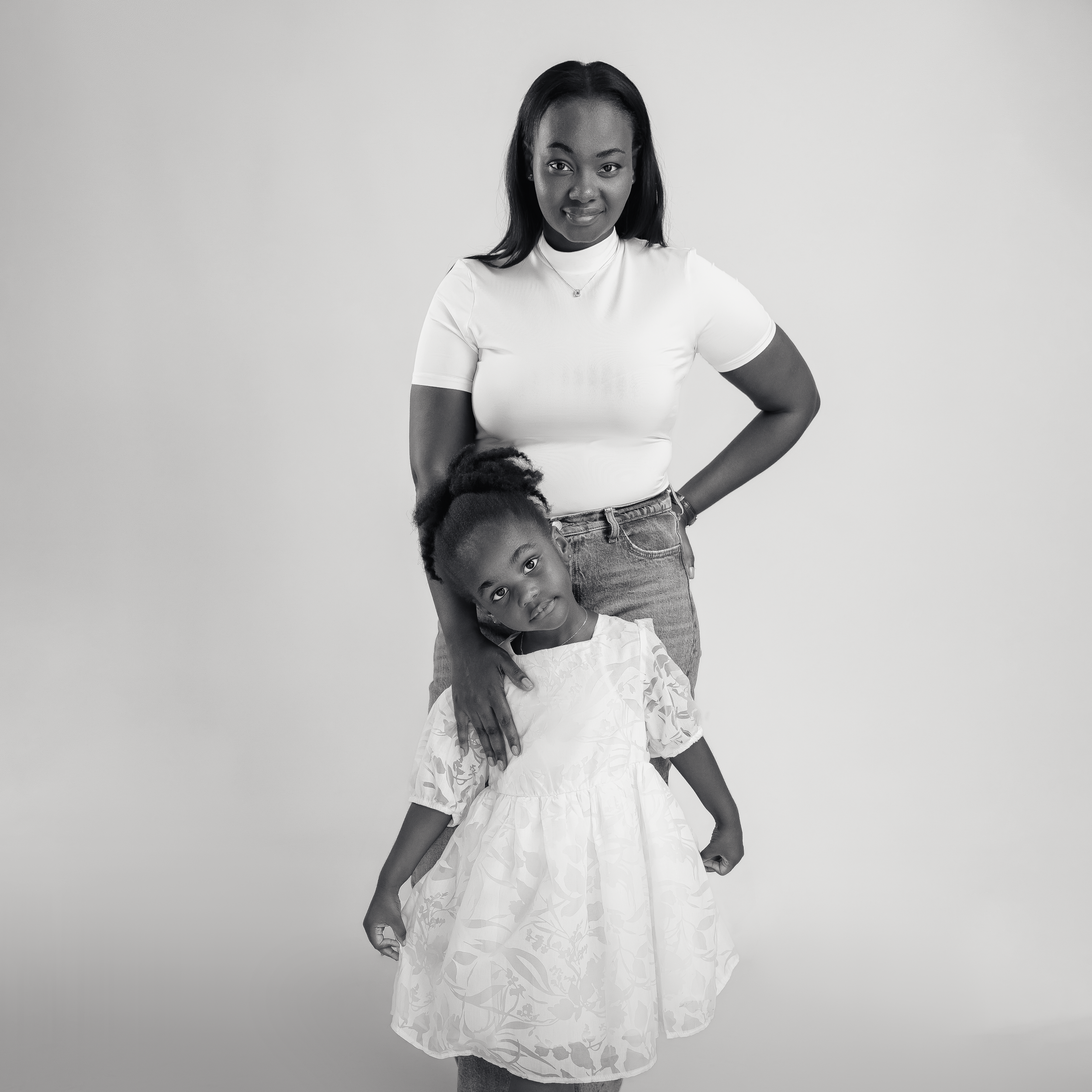 Playful studio portrait with two people in casual attire against light background.