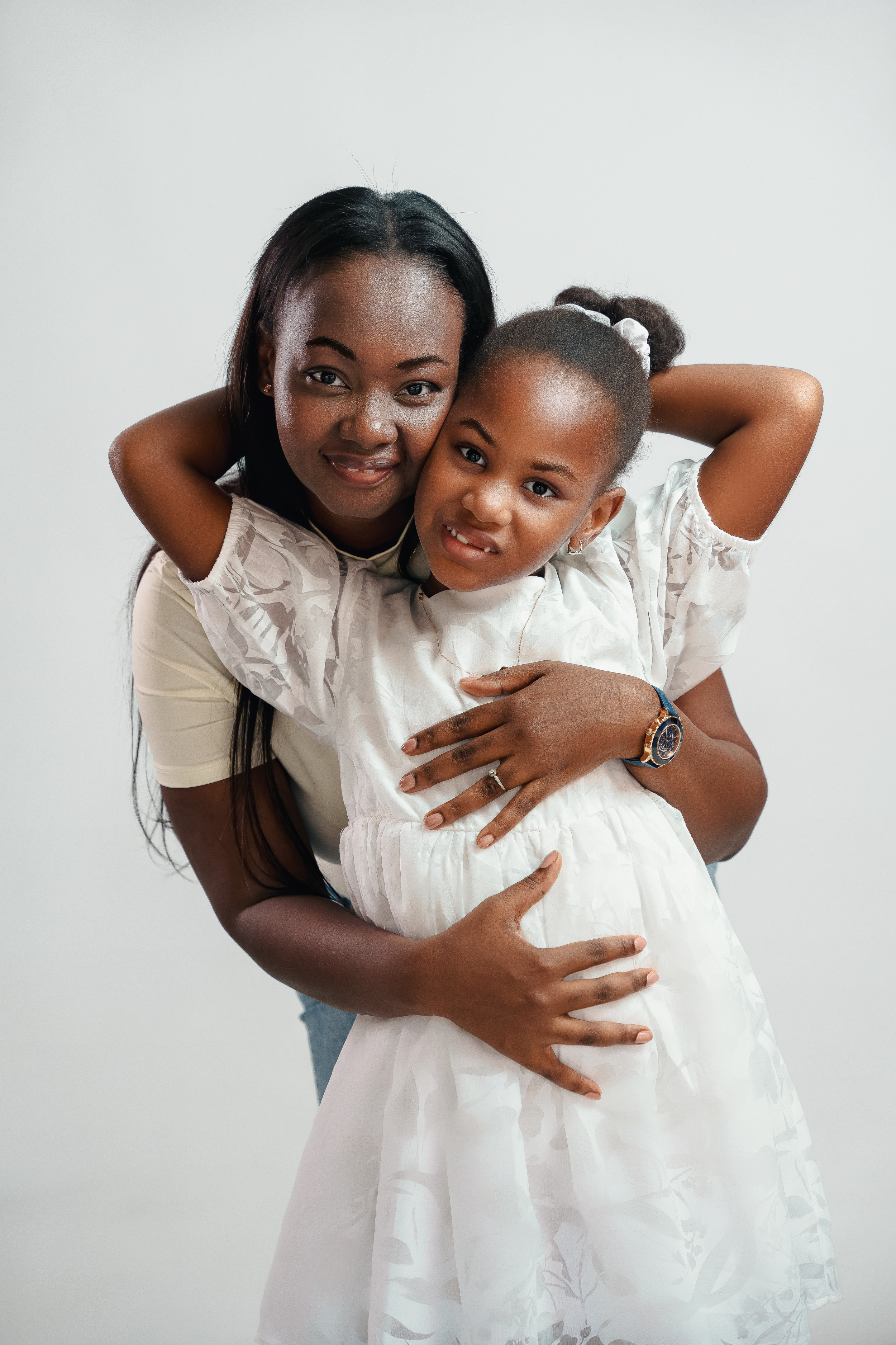 Heartwarming studio portrait showing embrace between two figures in white outfits.