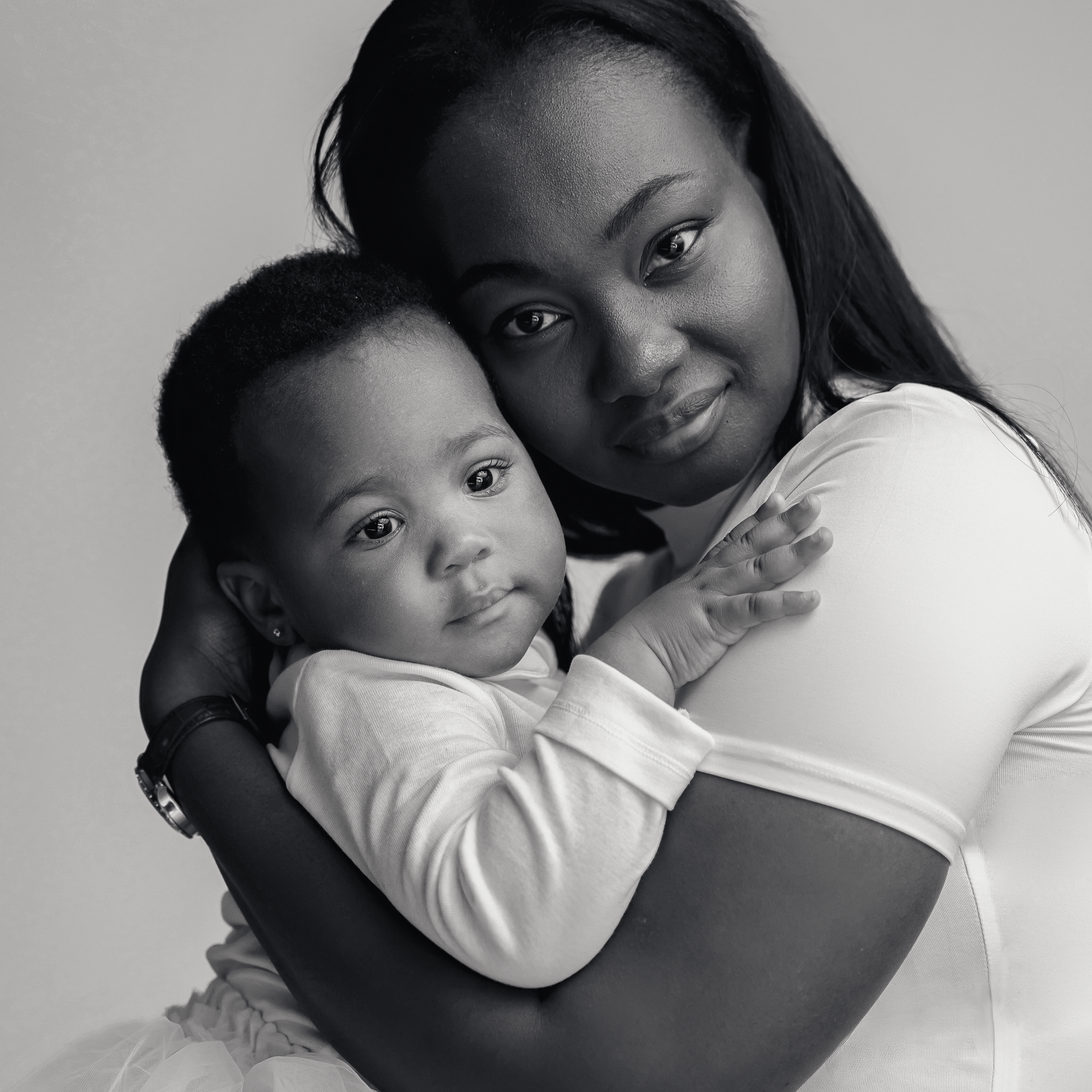 Tender embrace captured in black and white studio portrait against neutral background.