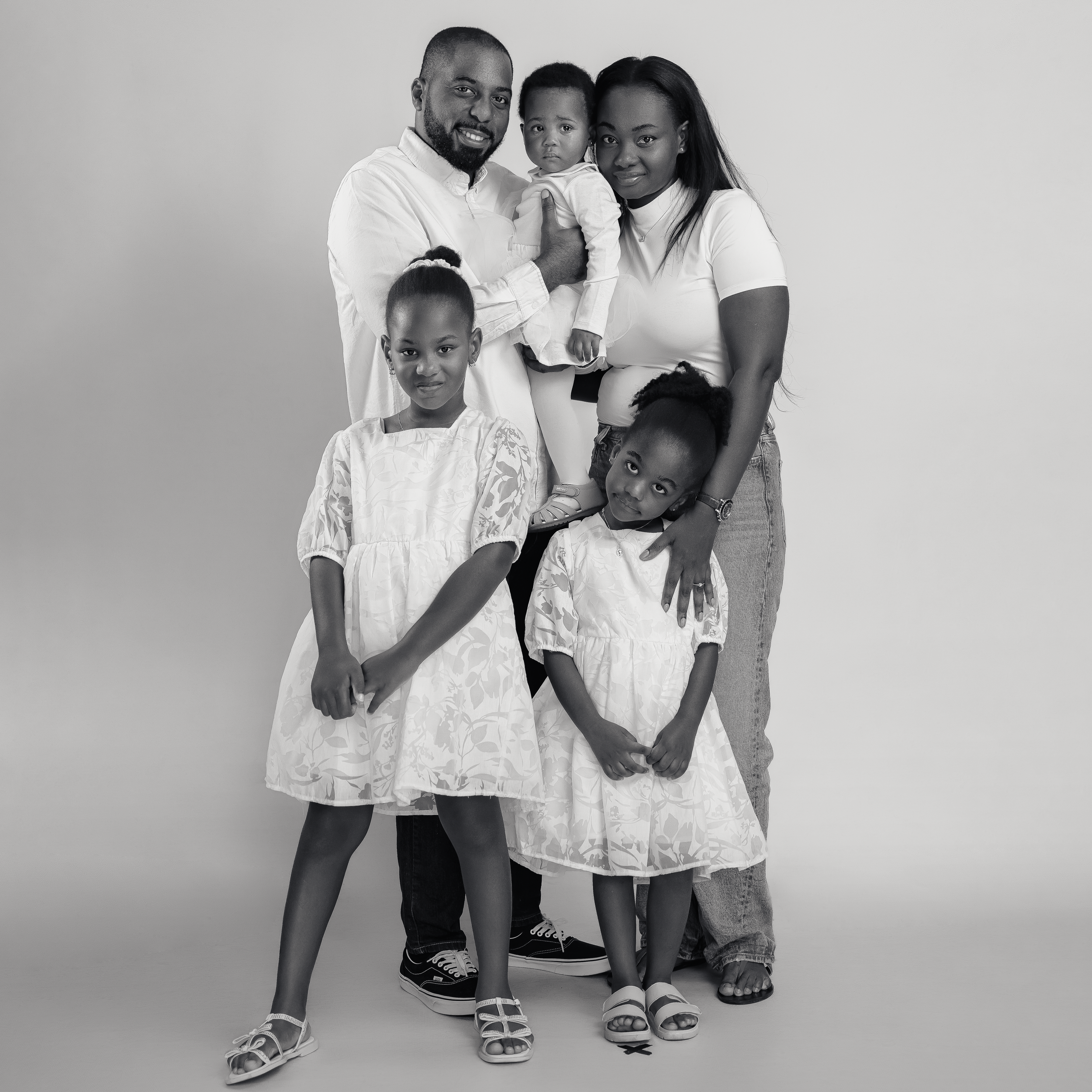 Black and white family portrait with everyone wearing coordinating white outfits.