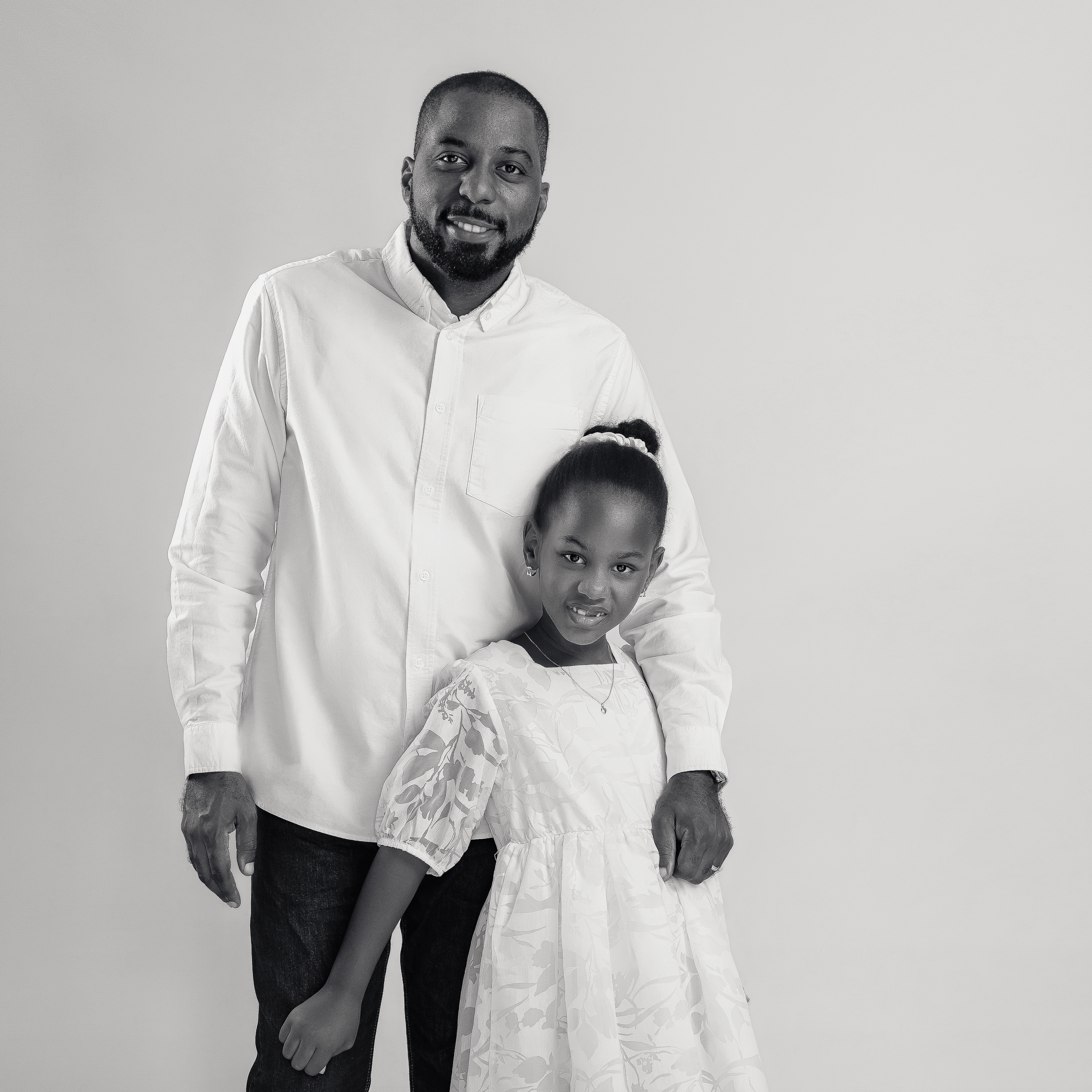 Sweet studio portrait of two people in white outfits against gray background.