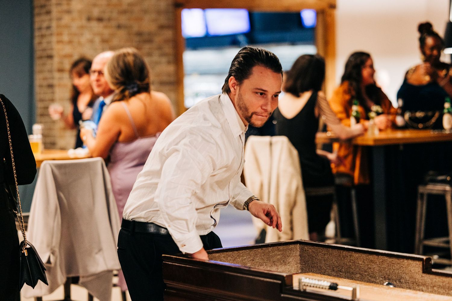 Bartender at a busy restaurant working behind a brick-walled bar counter during service.
