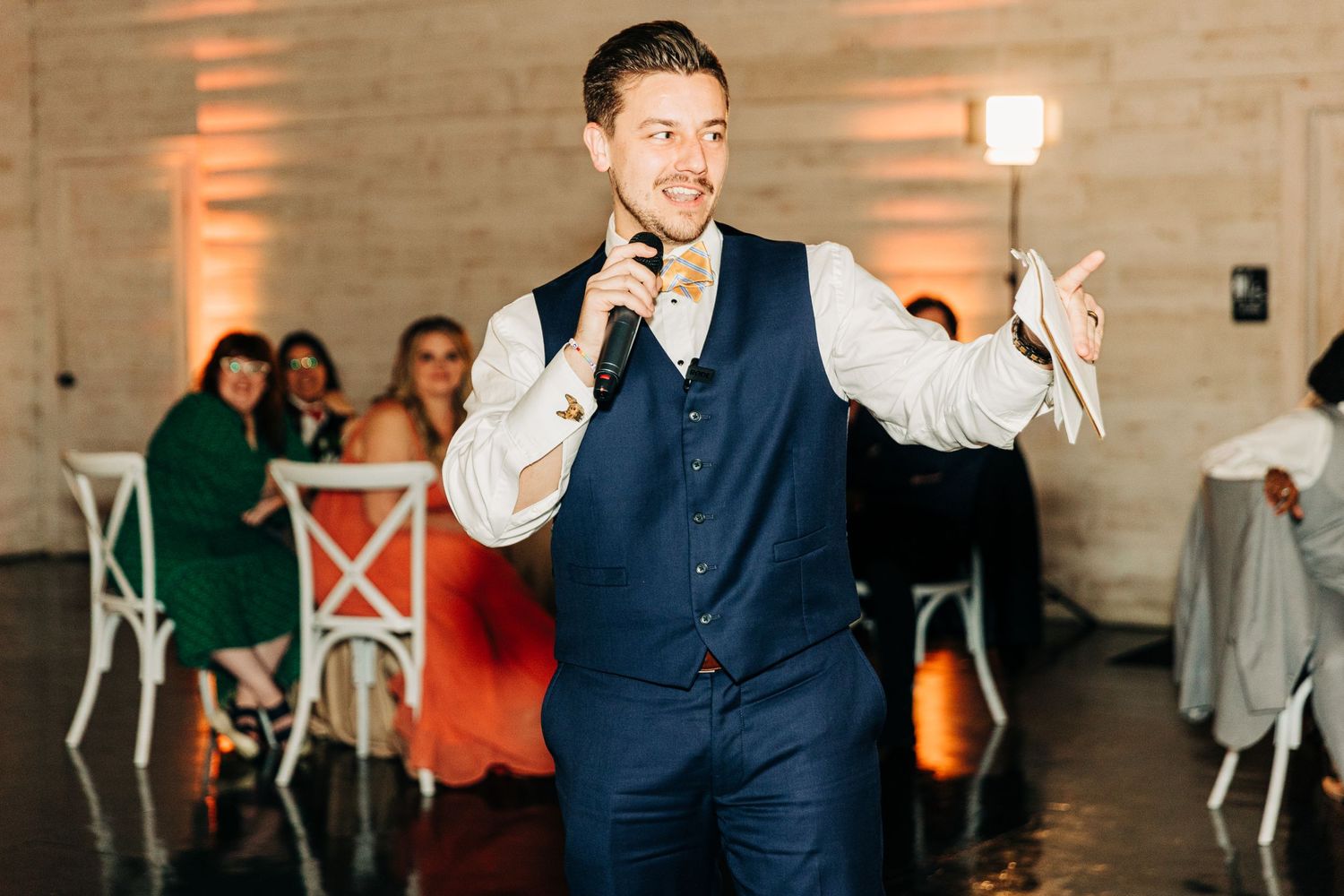 Wedding reception performer entertaining guests in navy vest and white shirt.