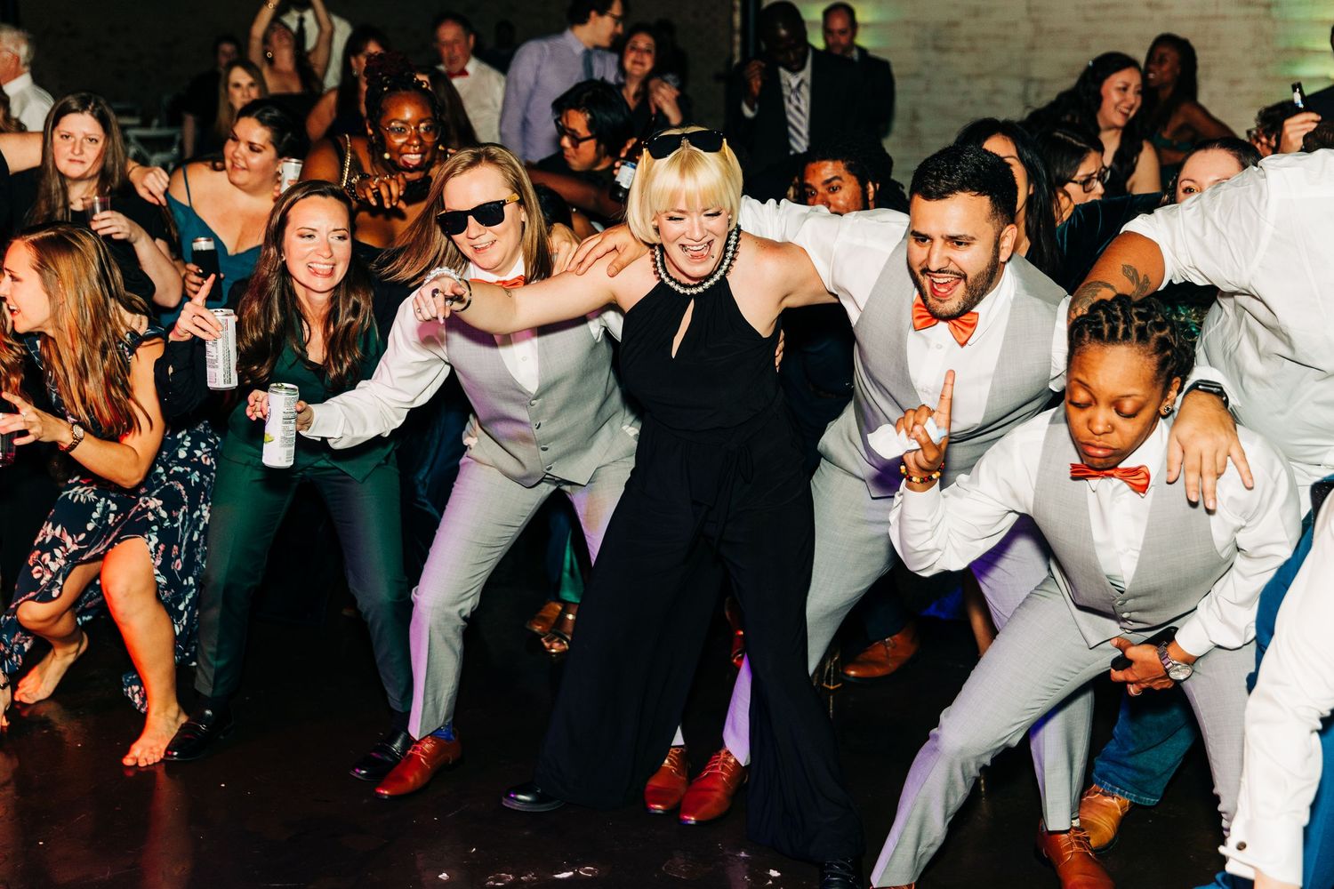 Wedding guests perform a choreographed line dance at a reception.