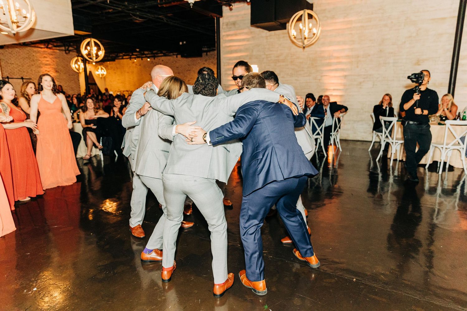Group of wedding guests dancing and celebrating on the reception dance floor.
