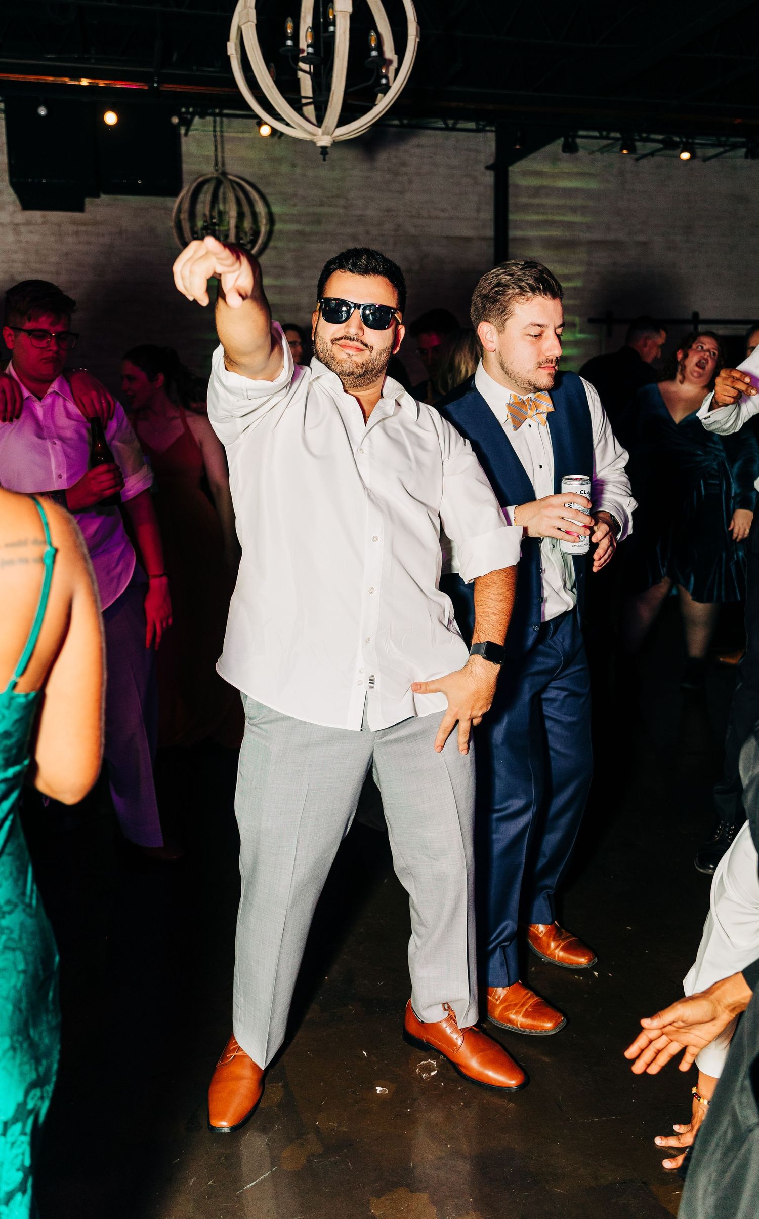 A guest in sunglasses dances enthusiastically at a wedding reception.