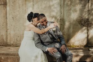 A playful wedding portrait showing laughter and embrace against a weathered wall.