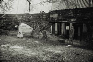 Black and white vintage photo of an old industrial building with stone walls and archways.