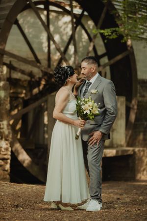 A romantic wedding moment captured under trees with soft natural lighting.