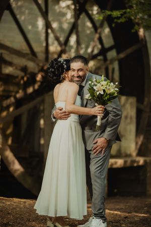A tender wedding moment shared between a couple in a wooded outdoor setting.