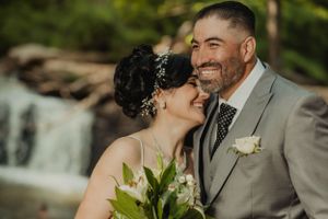 A joyful wedding portrait session near a waterfall with natural lighting.