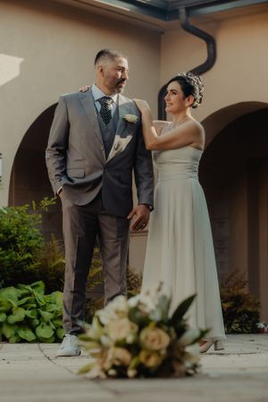 A candid wedding moment captured in an outdoor courtyard with arched architecture.