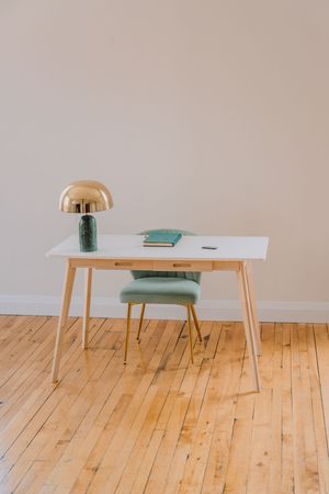 Minimalist dining set with white table, mint green bench seat, and wooden legs on light hardwood flooring.
