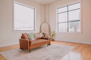 Empty room interior with large windows, hardwood floors, and white walls showing multiple angles of the same space.
