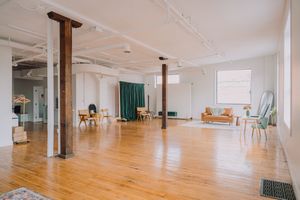 Panoramic view of an empty modern dance studio with wooden floors and white walls featuring mirrors and ballet barres.
