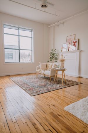 Bright minimalist studio space with hardwood floors, large windows, and a decorative area rug in a modern setting.