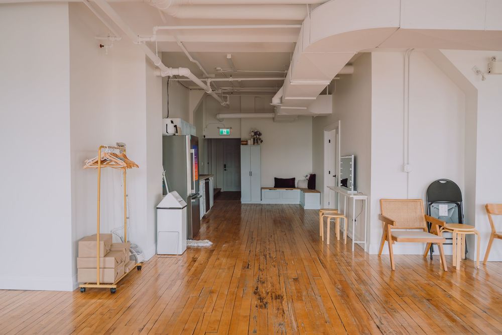 Modern loft-style interior with wooden floors, white walls, and minimalist furniture in an open concept space.