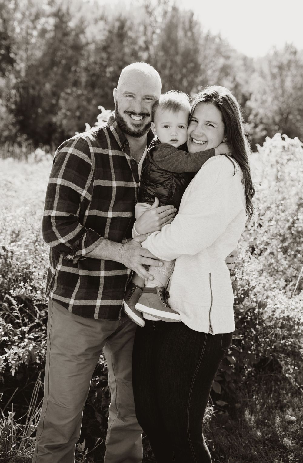 Classic black and white family portrait capturing genuine smiles in an outdoor setting.