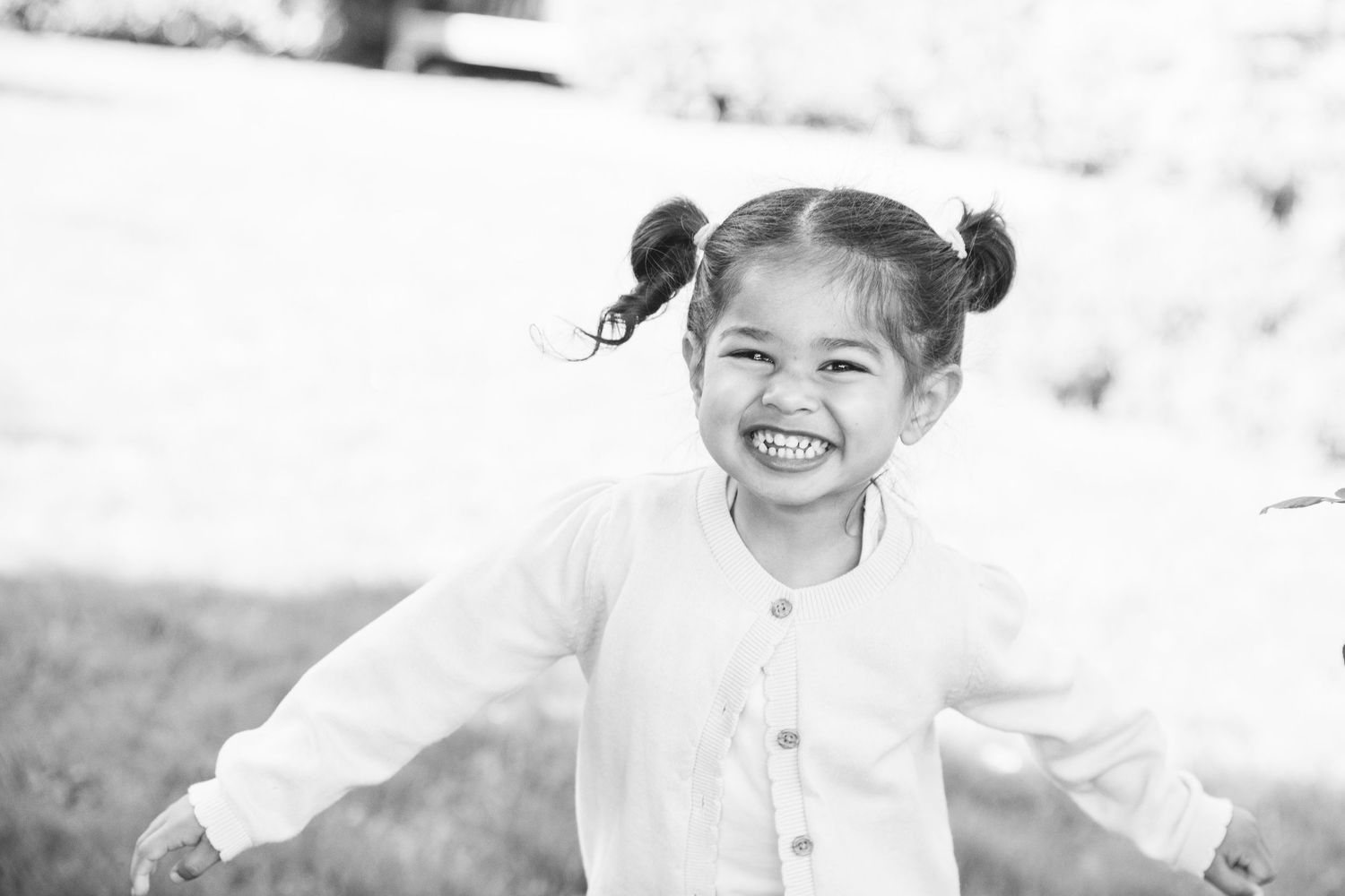 A candid black and white portrait capturing pure joy and laughter while wearing a white button-up shirt.