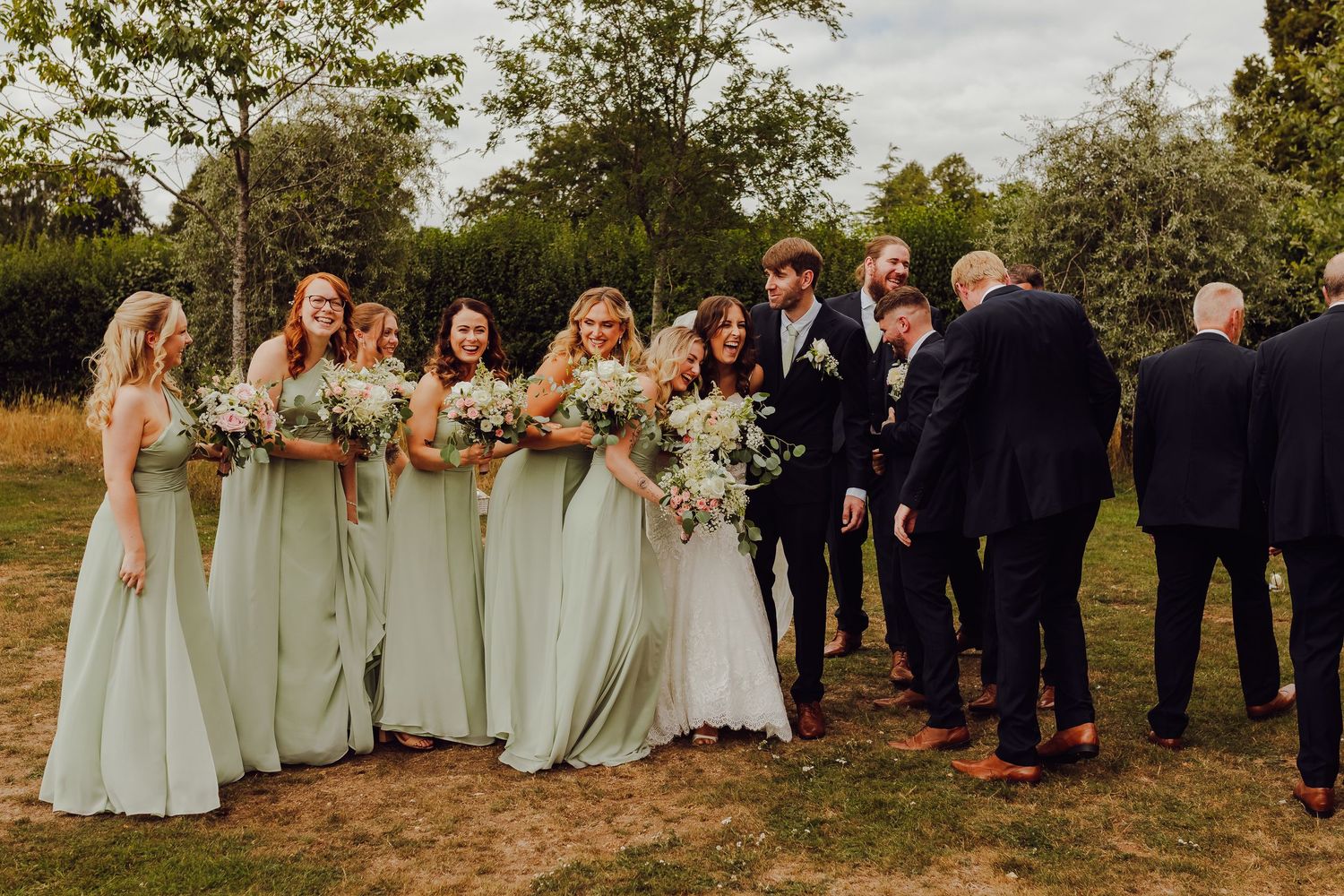 Wedding party portrait with bride and groom surrounded by family and friends.
